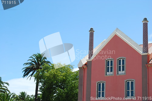Image of Pink traditional building with palm trees garden