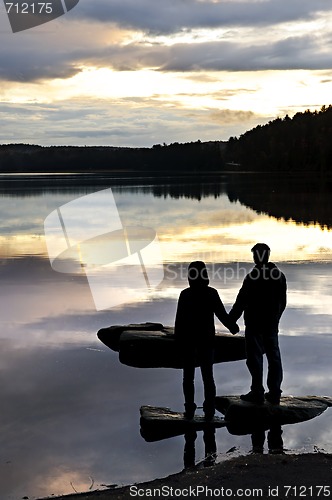 Image of Silhouette of people watching sunset at lake