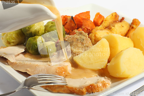 Image of Pouring gravy on a roast turkey meal