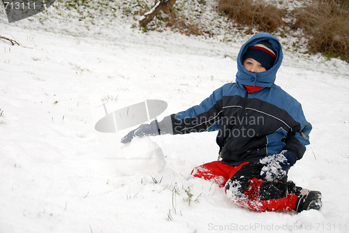 Image of Winter time. Young boy sit on snow.