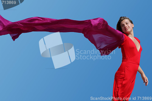 Image of young women with red fluttering scarf on blue sky background