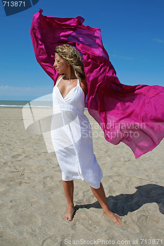 Image of young women in white on beach with red fluttering scarf