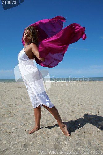 Image of young women in white on beach with red fluttering scarf