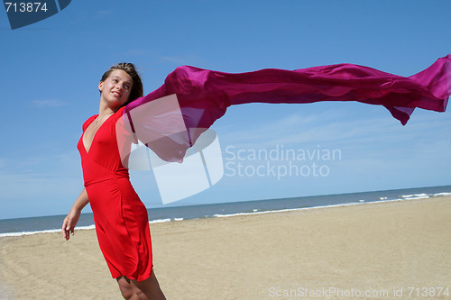 Image of young women on beach with red fluttering scarf