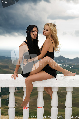 Image of Two sexy young women sitting on a white handrail