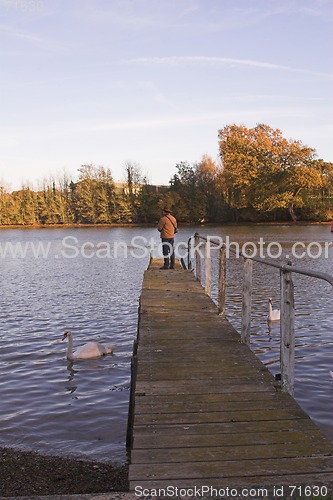 Image of Man standing on jetty over river