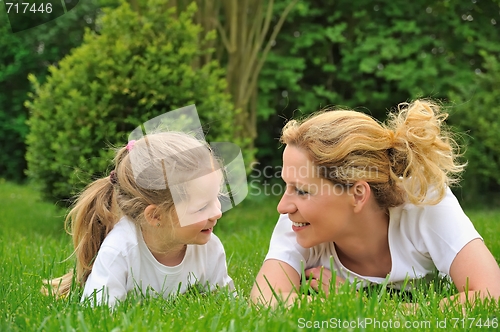 Image of Young mother and daughter laying on the grass