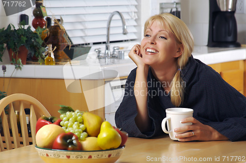 Image of Woman with Cup of Coffee in Kitchen Smiling