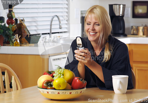 Image of Woman In Kitchen Using Cell Phone