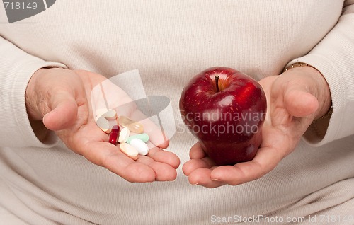 Image of Senior Woman Holding Pills and Apple