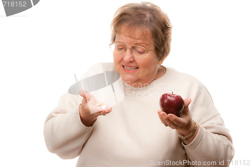 Image of Confused Senior Woman Holding Apple and Vitamins