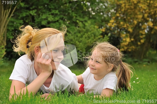 Image of Young mother and daughter laying on the grass