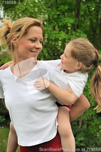 Image of Young mother giving her child piggyback ride