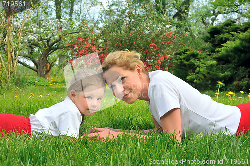 Image of Young mother and daughter laying on the grass