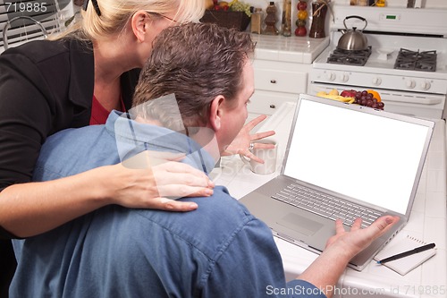 Image of Couple In Kitchen Using Laptop with Blank Screen