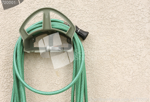 Image of Garden Hose Hanging on Stucco Wall
