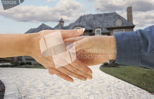 Image of Man and woman shaking hands in front of a new house.