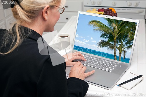 Image of Woman In Kitchen Using Laptop - Vacation
