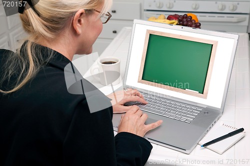 Image of Woman In Kitchen Using Laptop - Chalkbaord