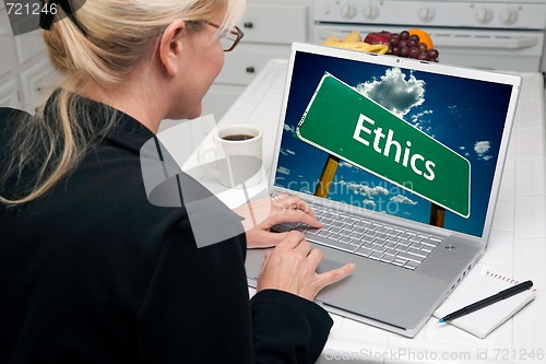 Image of Woman In Kitchen Using Laptop with Ethics Sign