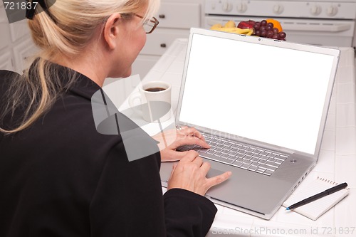 Image of Woman In Kitchen Using Laptop with Blank Screen