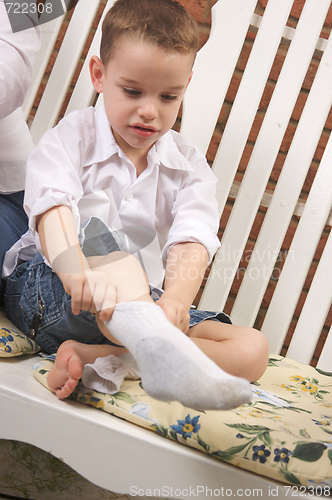 Image of Adorable Young Boy Getting Socks On