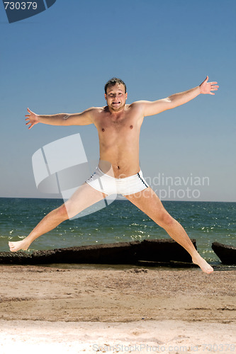 Image of Bizarre young man jumping on a beach
