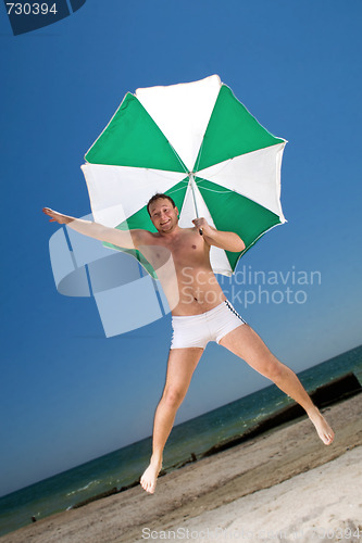 Image of Bizarre young man with umbrella on a beach