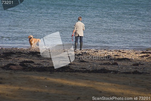 Image of woman & dog on playing on the seashore