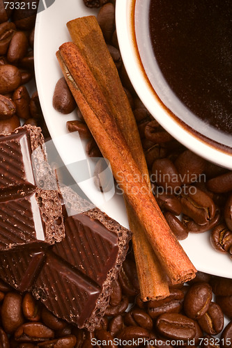 Image of cup of coffee, beans, cinnamon and black chocolate