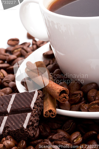 Image of cup of coffee, beans, cinnamon and black chocolate