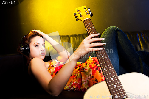 Image of Beautiful woman with headphones and guitar