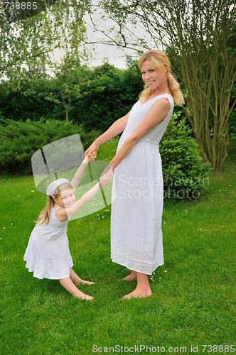 Image of Young mother and daughter playing in meadow