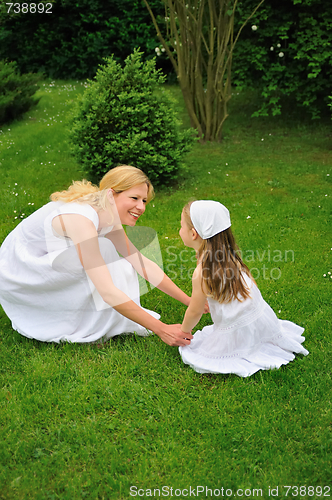 Image of Young mother and daughter playing in meadow