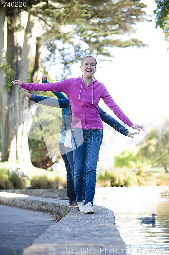 Image of 3 Tween Girl Balancing On Wall By Pond