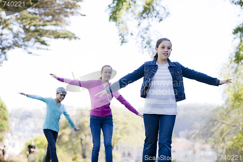 Image of 3 Tween Girl Balancing On Wall By Pond