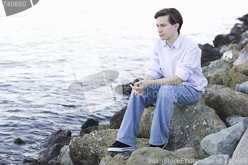 Image of Teenage Boy Sitting On Rocks By Ocean