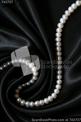 Image of White pearls on the black silk as background 