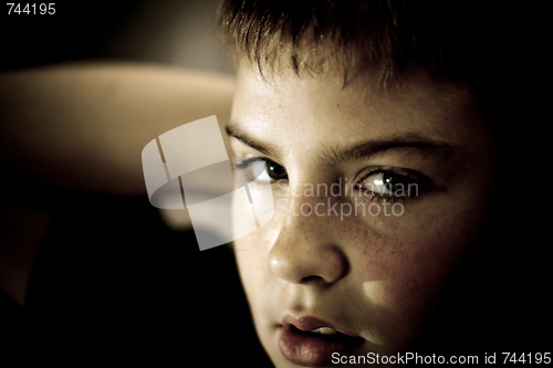 Image of Young boy looking up with hope in his eyes low key sephia tonned