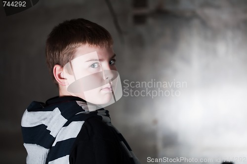 Image of Boy looking over the shoulder against grunge background lit with flash