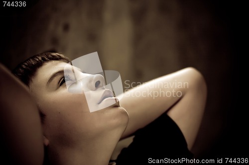 Image of Young boy looking up with hope in his eyes sepia toned low key