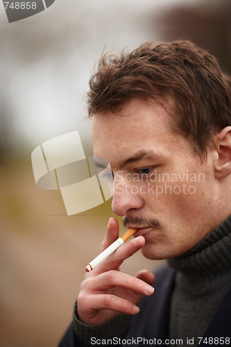 Image of Trendy young man smoking an unhealthy cigarette