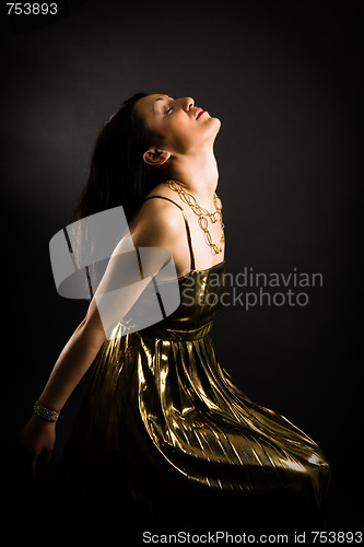 Image of Relaxed woman in gold evening dress on black