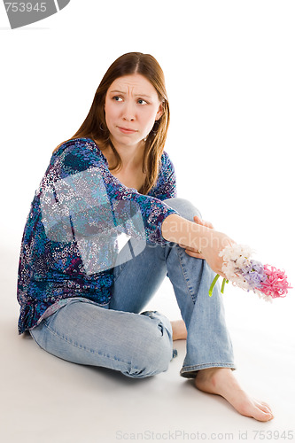 Image of Lonely woman siting on the flor with flowers in hand