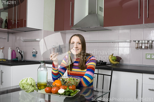 Image of Woman eating salad in the kithen