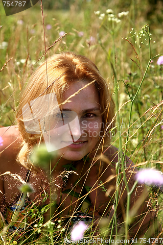 Image of The girl with red hair on a meadow among a grass