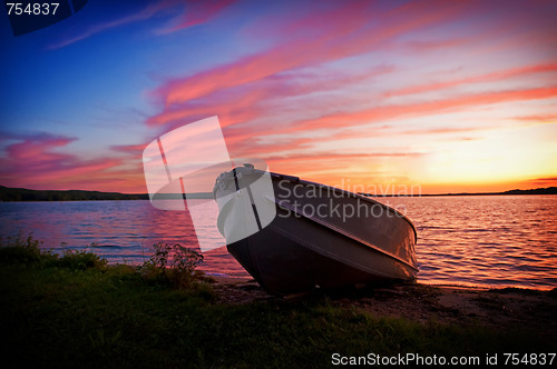 Image of Image of fishing boat on shore of lake at sunset