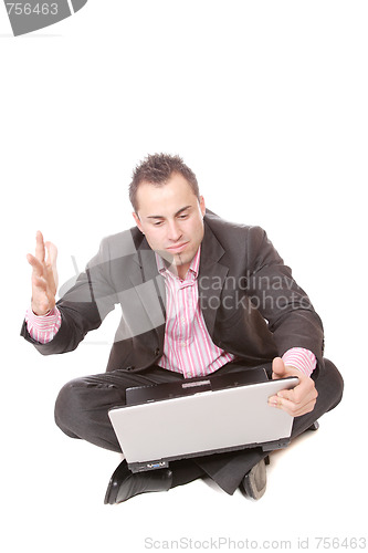 Image of Young man with laptop sits on floor.