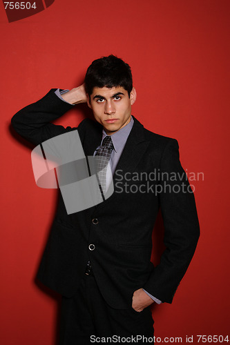 Image of Young man in suit over red wall