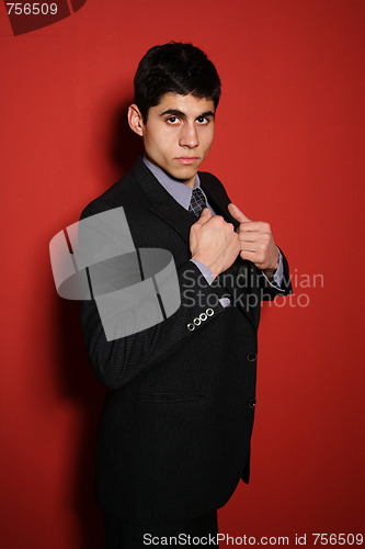 Image of Young man in suit over red wall